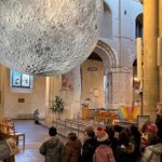 Children looking at a model of the moon in a cathedral